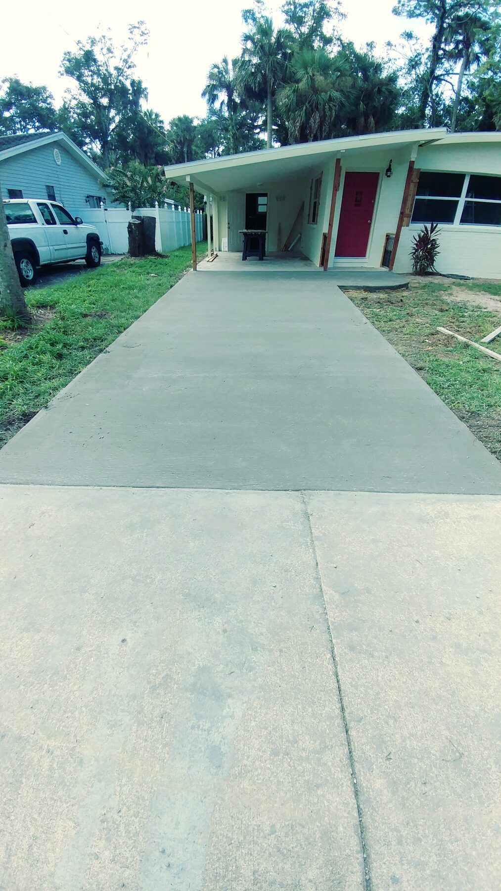 Newly poured residential concrete driveway leading to a carport, finished by Revive Services in Central Florida