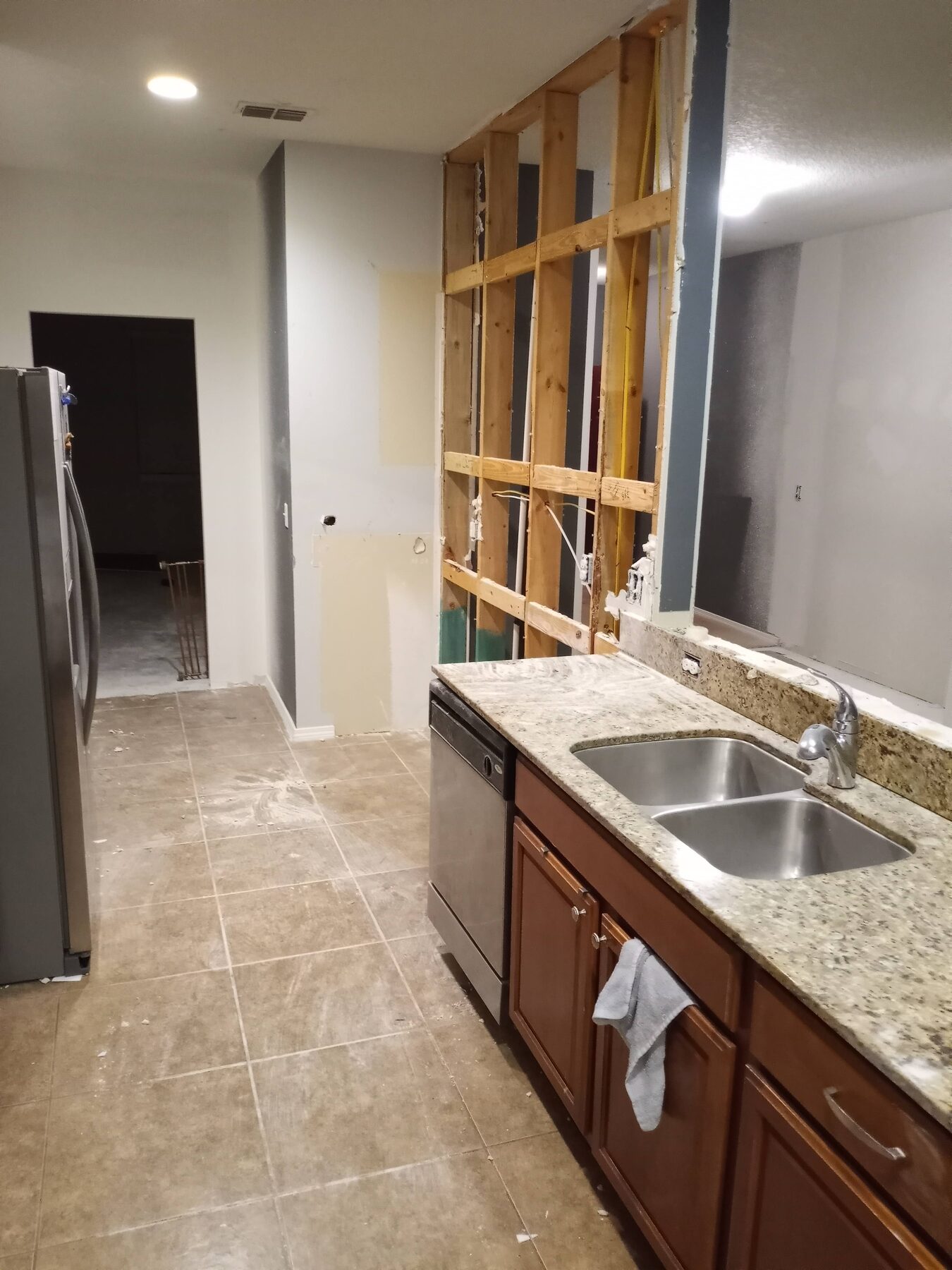 Cleaned kitchen tear-out with bare wall framing, original sink remaining, ready for new cabinetry install