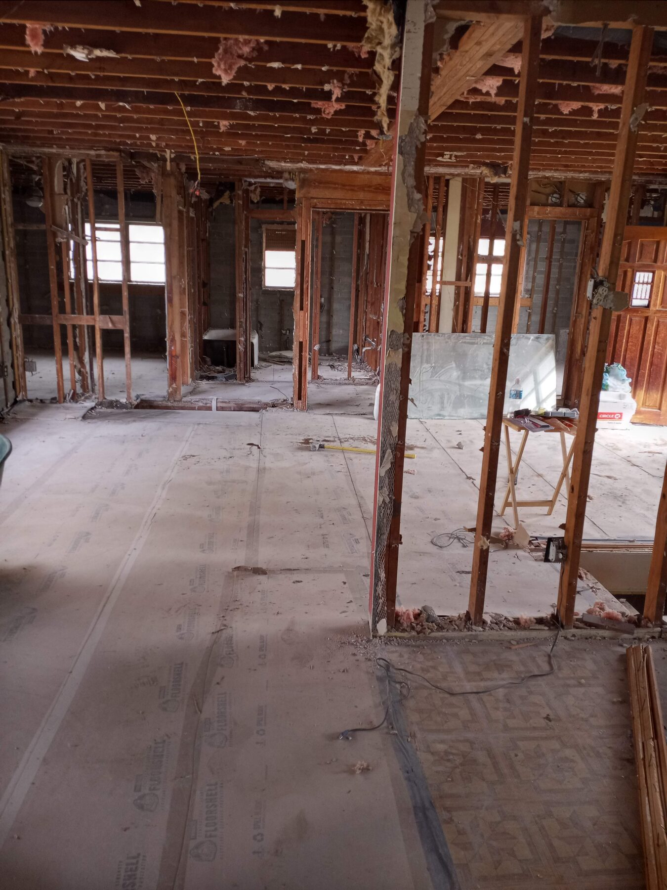 Single-family home interior fully gutted to studs and roof rafters with drywall, insulation, and finishes removed
