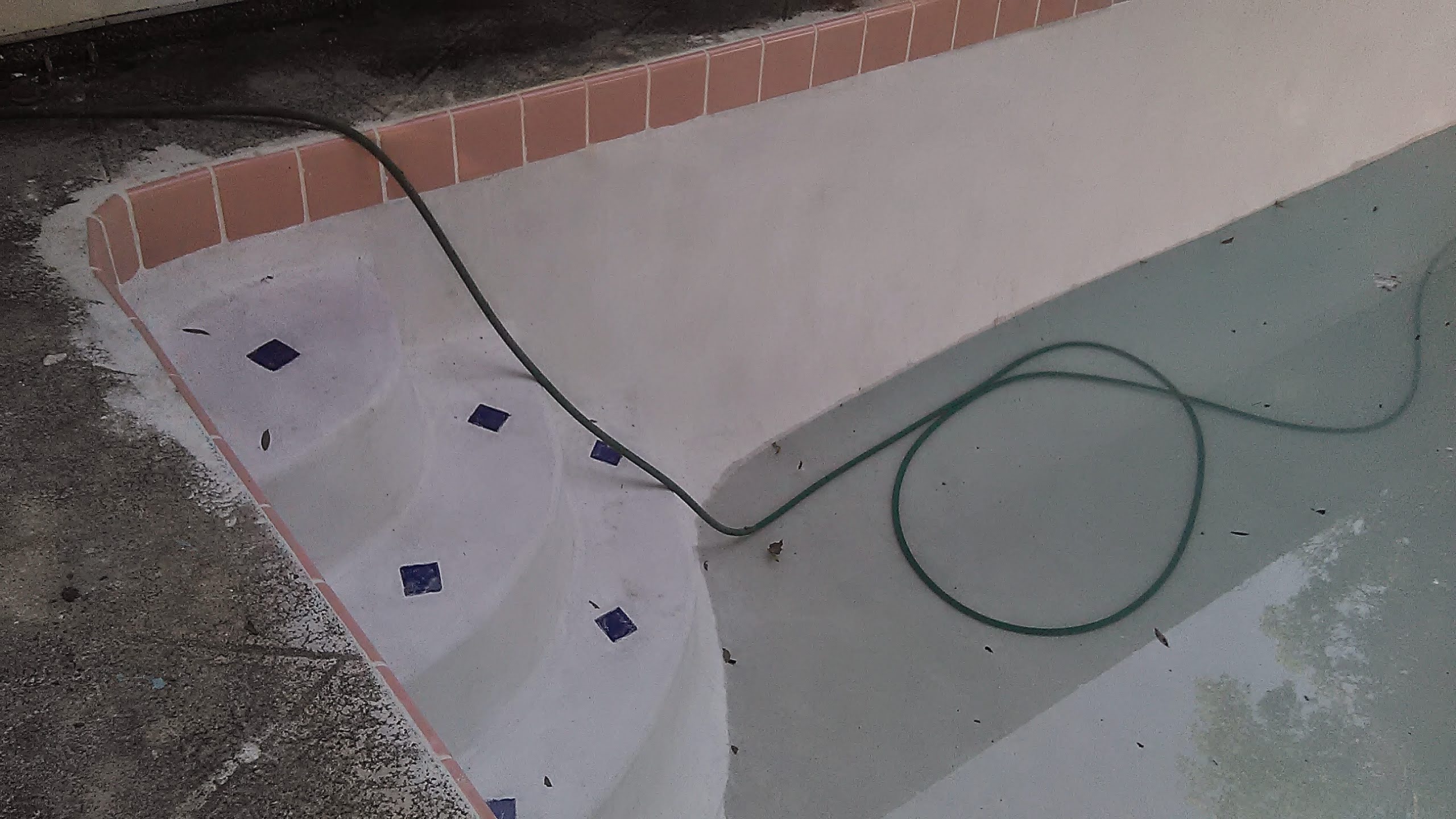Close-up of pool steps with custom blue diamond tile inlays set into the white plaster