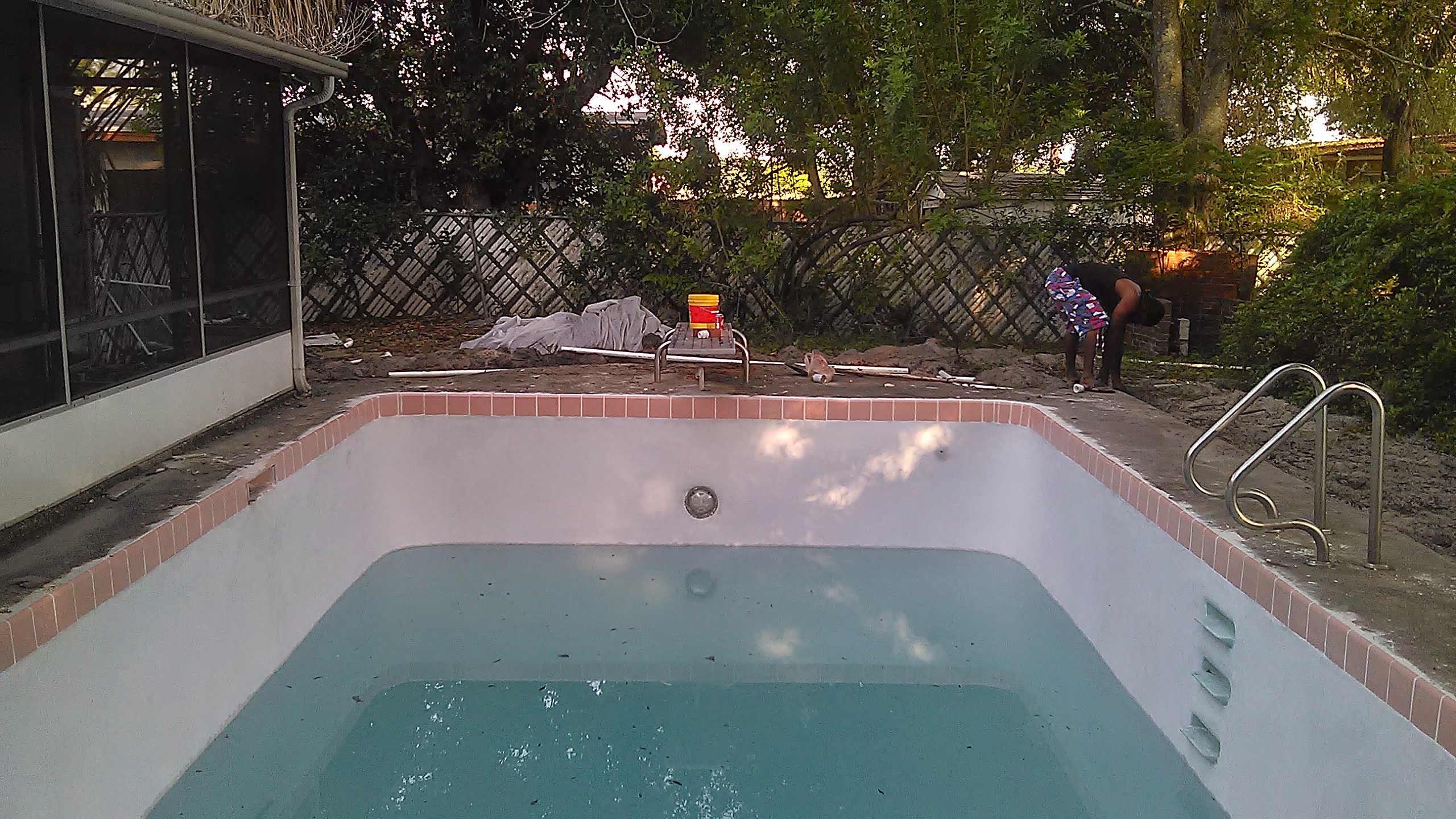 Residential pool with freshly applied white plaster and pink tile coping during a Central Florida resurfacing job